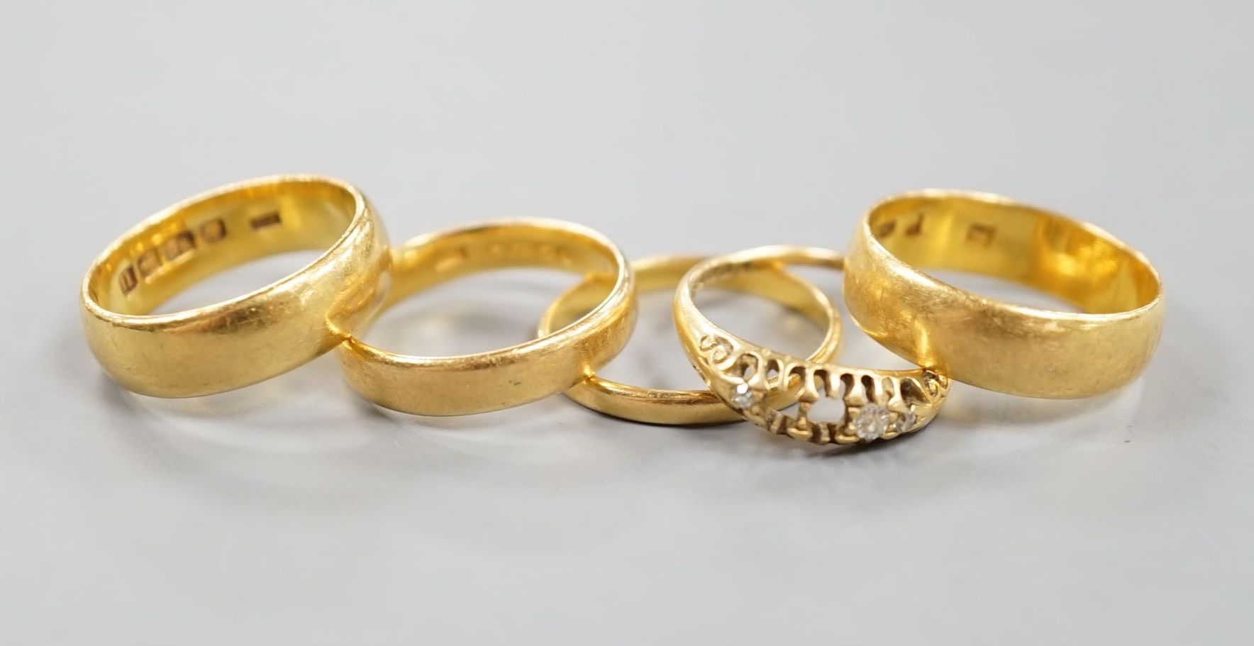 Four assorted mainly early 20th century 22ct gold wedding bands and an 18ct and diamond chip set ring(stones missing